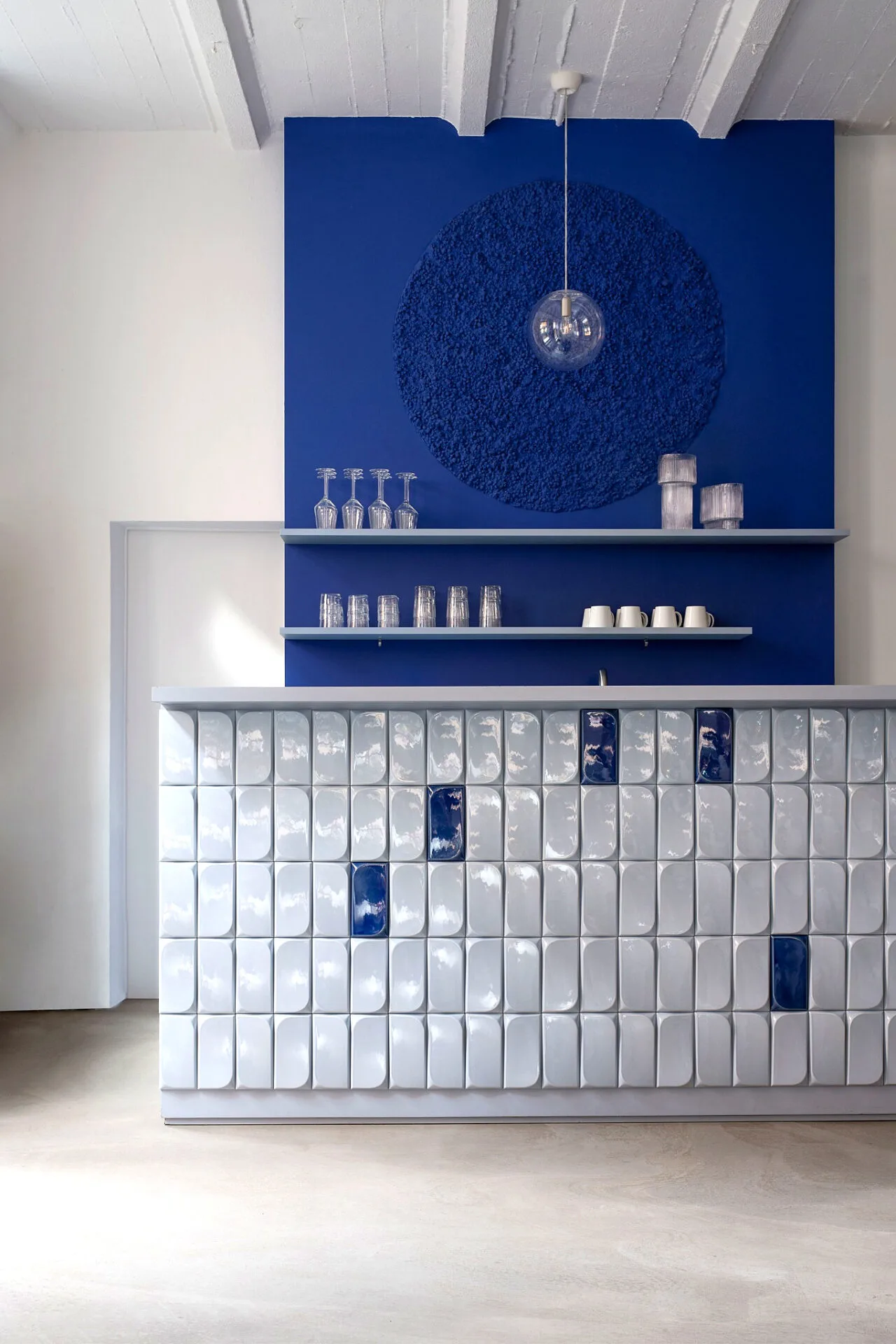 ABERJA Studio Office mit blauer Wand, keramischer Fliesentheke und maßgefertigter Innenarchitektur.