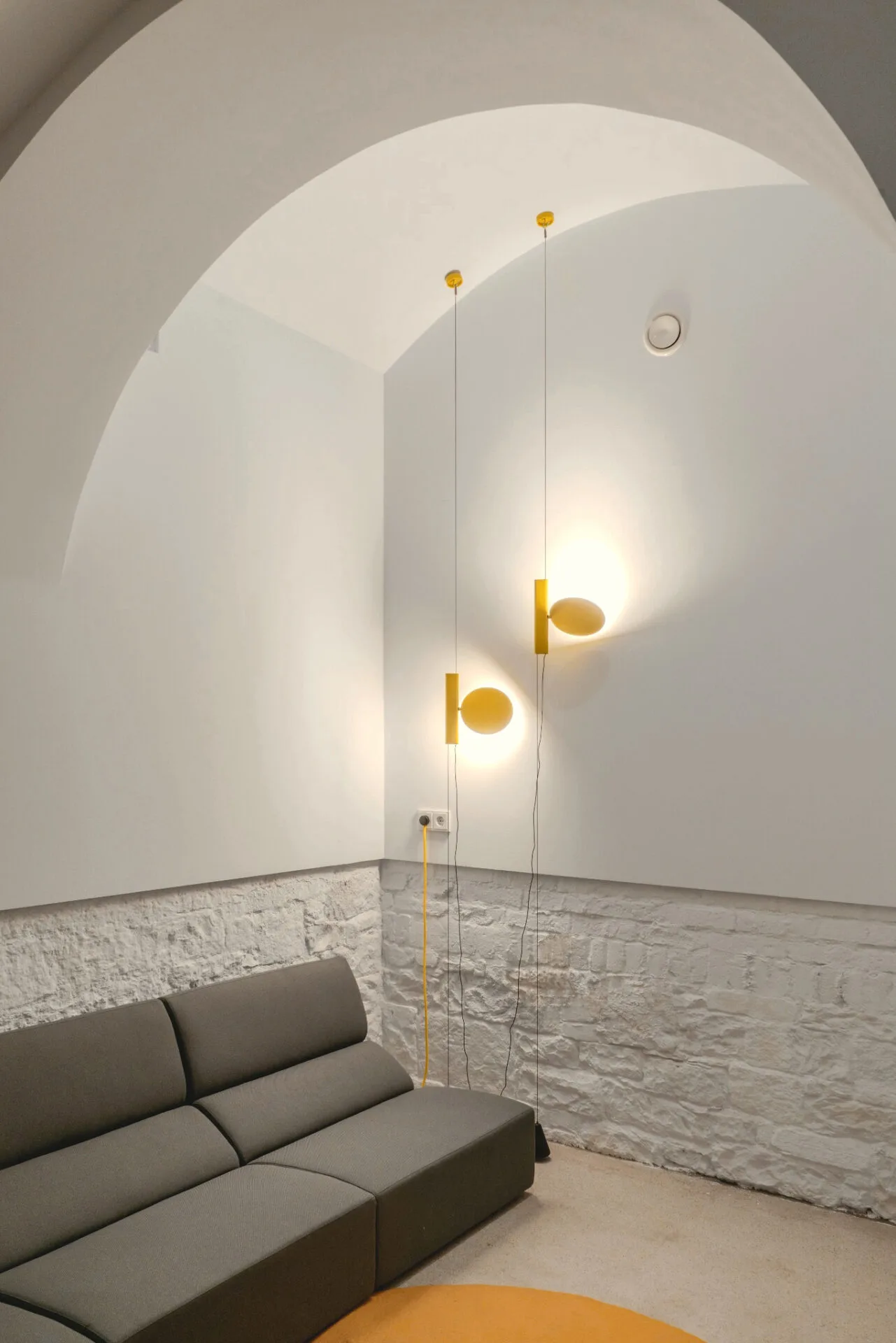Lounge im Retablo Coffee mit Sofa, weißer Ziegelwand und gelben leuchtenden Wandobjekten.